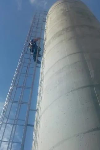 Profissional na escada de uma torre de água